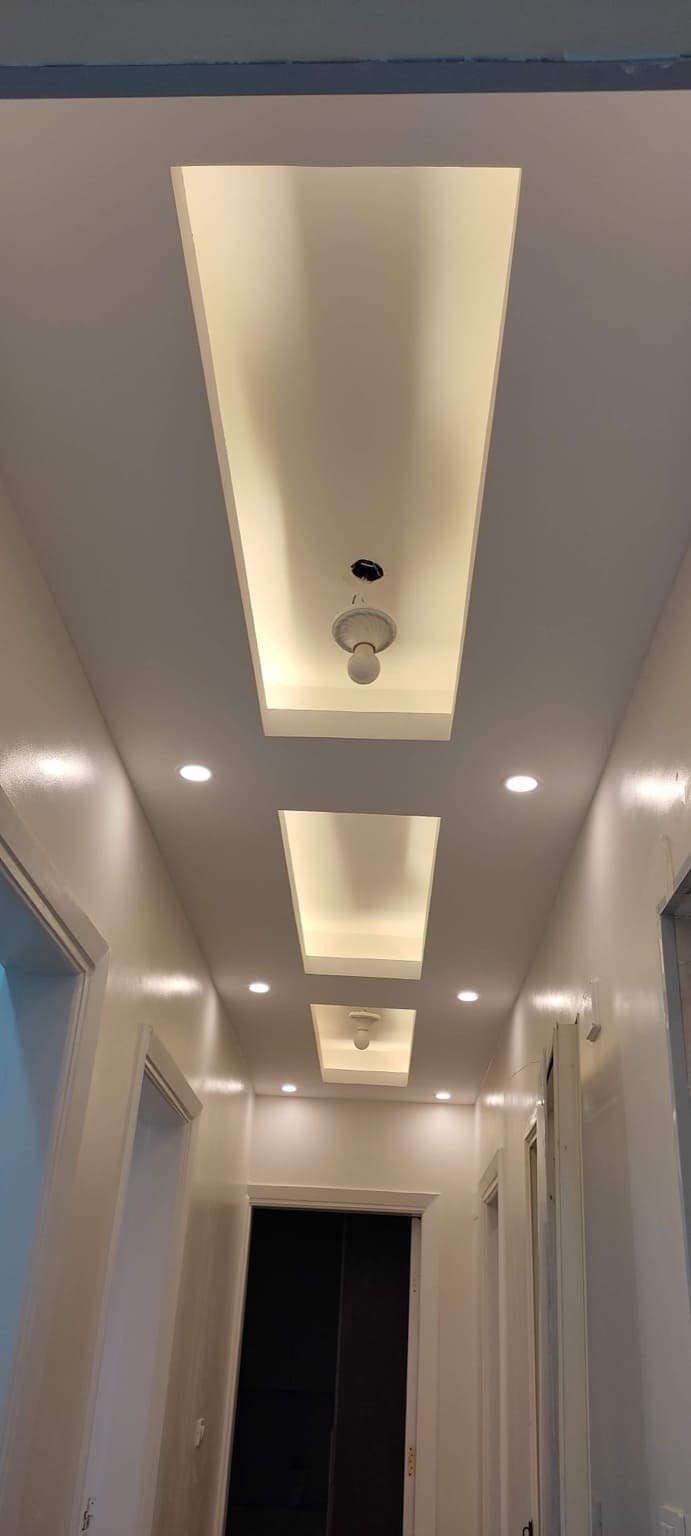 Large-scale commercial gypsum board ceiling installation with integrated lighting fixtures and suspended framework