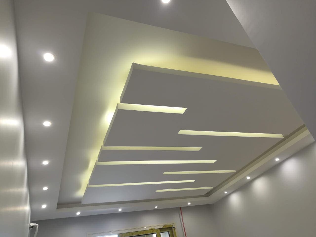 Gypsum board installation around large windows with precise measurements and clean finishing